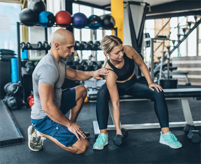 A girl doing dumbell rows in red leggings and white skinny that has a nice floral colored tattoo on her right shoulder