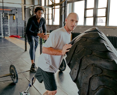 A strong man trying heavy wight shoulder raises and his facial expressions shows how heavy that is